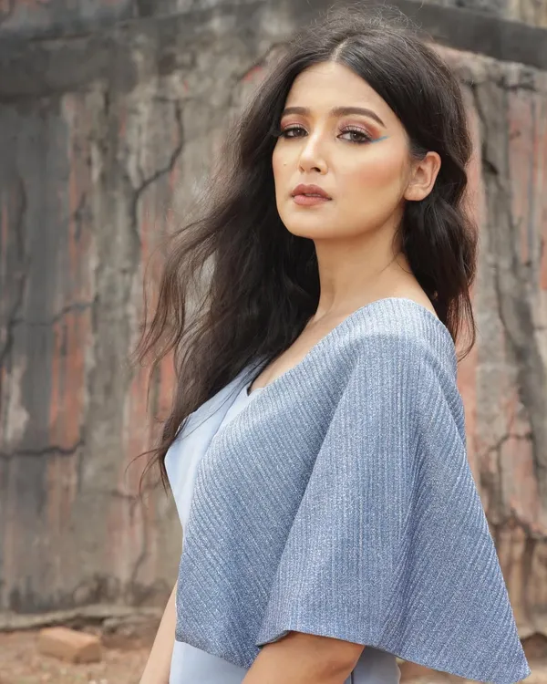 A designer shoot against a rustic, architectural backdrop. I styled this blue jumpsuit with a unique silhouette to create a strong contrast with the textured, earthy tones of the location.