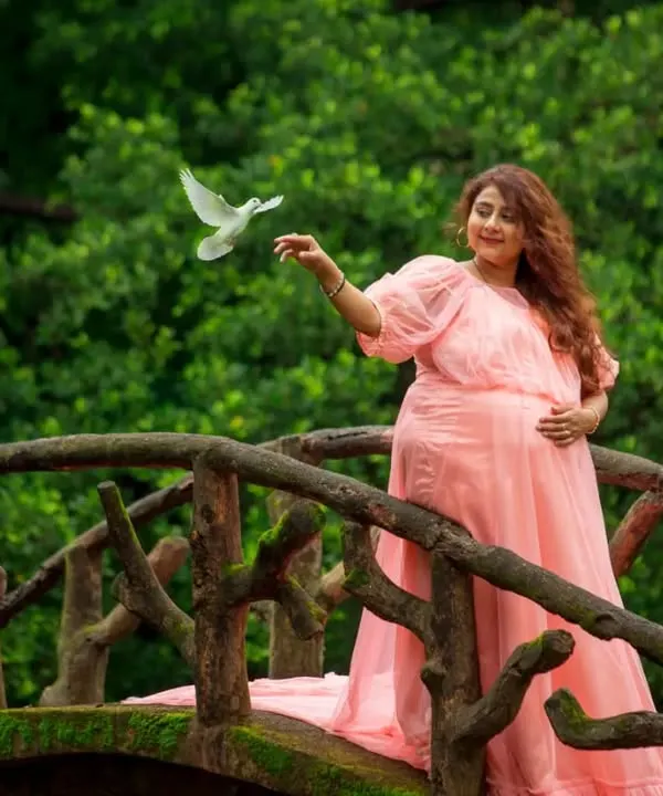 This beautiful mom-to-be is glowing in a soft peach maternity gown. The design is focused on providing a comfortable, flattering fit that drapes beautifully over the baby bump, perfect for capturing those serene moments.