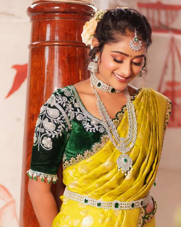 Elevate your saree with this luxurious dark green velvet blouse. It features heavy silver embroidery on the sleeves, available to rent separately for your special event.