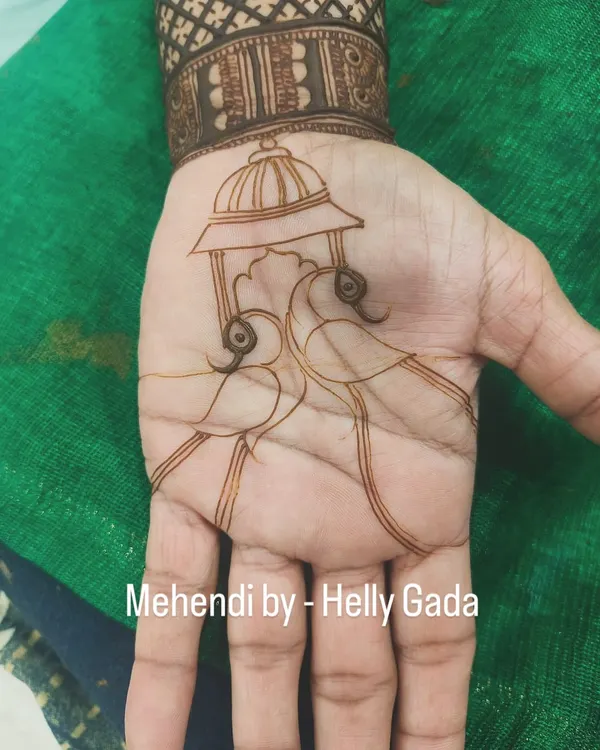 The beginning of a beautiful peacock design. This shows the clean, simple outline of two peacocks under a traditional 'doli' or palanquin, a classic motif in wedding mehndi.