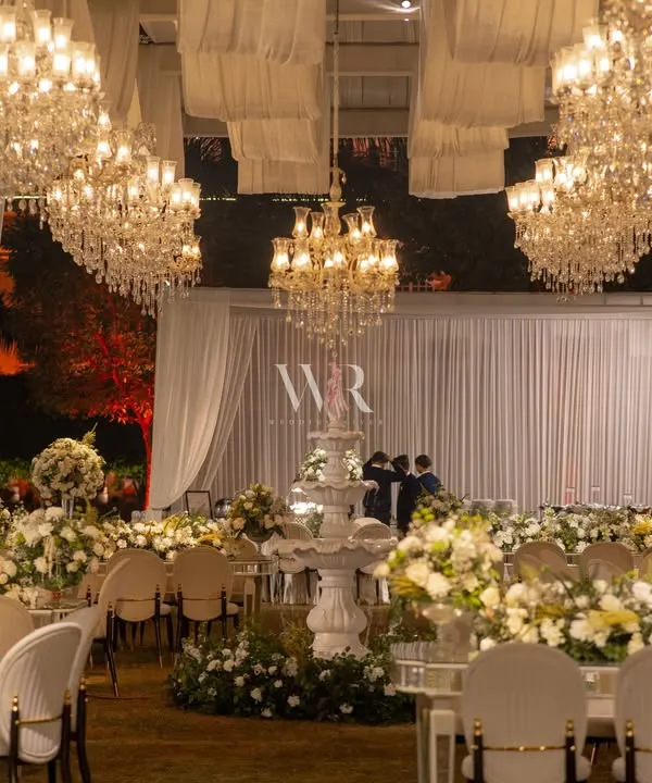 I believe in creating spaces that feel like living paintings. For this reception, we transformed an open lawn into a dreamscape under a canopy of soft ivory drapes and more than forty cascading crystal chandeliers, bathing the entire evening in a warm, magical glow.