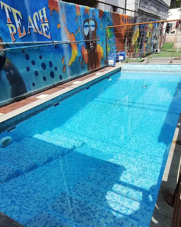 A view of our sparkling clean, tiled pool with its easy-entry steps. The "TEACH PEACE" mural in the background reflects the calm and happy vibe we cultivate.