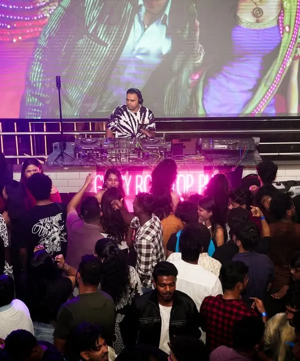 A wide shot showing the full scale of my VJ setup. With me at the decks and a massive LED screen behind me playing synced visuals, the entire venue is transformed into a dynamic audio-visual spectacle.
