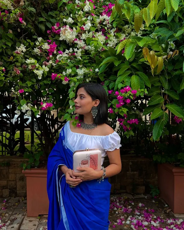 A perfect example of modern ethnic style. Here, my abstract face art clutch is paired with a beautiful blue saree and a statement oxidized silver necklace, showing how my accessories can complete any look.