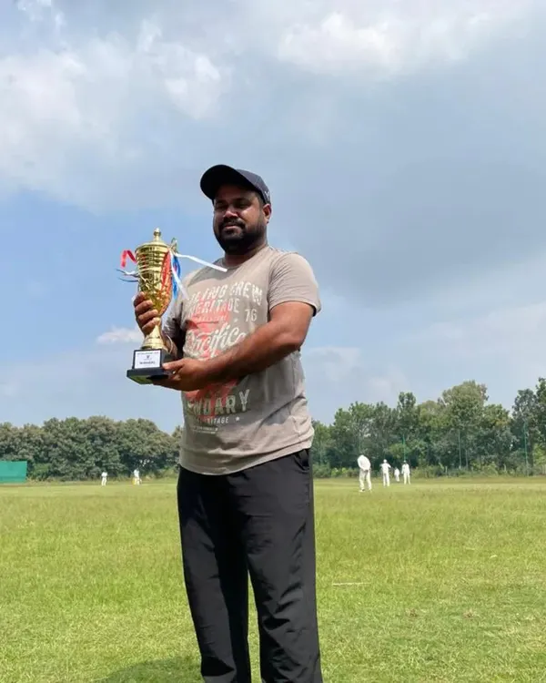 A proud coach holds the championship trophy after our U12 team's victory. Our coaches' dedication is a huge part of our players' success.