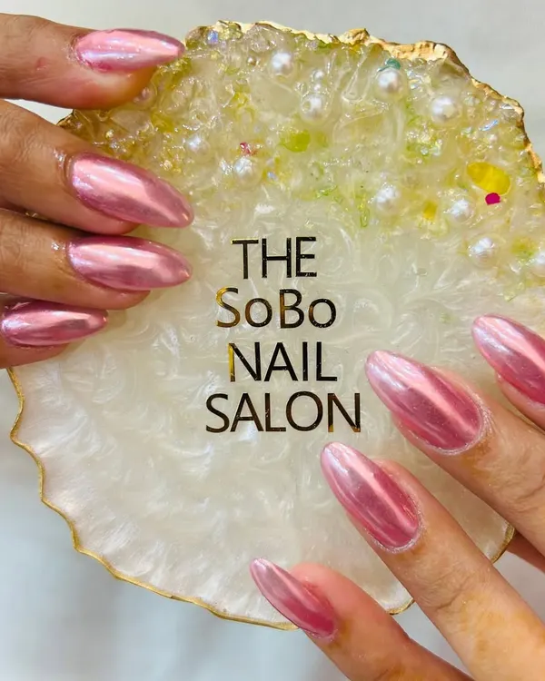 A stunning example of a full chrome manicure. These long, almond-shaped nails are coated in a vibrant pink chrome powder, giving them a liquid metal look that is incredibly reflective and glamorous.