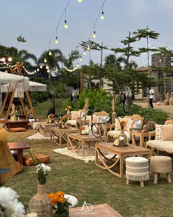 A wide view of a bohemian dreamscape I created. The lawn is filled with various seating arrangements, from low tables with floor cushions to comfortable lounge sets, all under a canopy of twinkling lights.