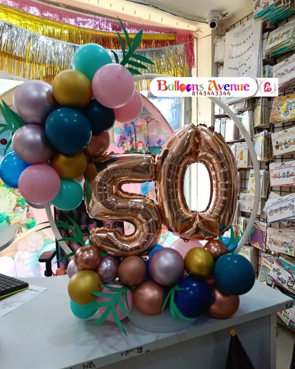 A compact and elegant tabletop balloon decoration for a 50th milestone celebration. This arrangement features a small ring with balloons and a large rose gold number '50', perfect for an office desk or a small party at home.