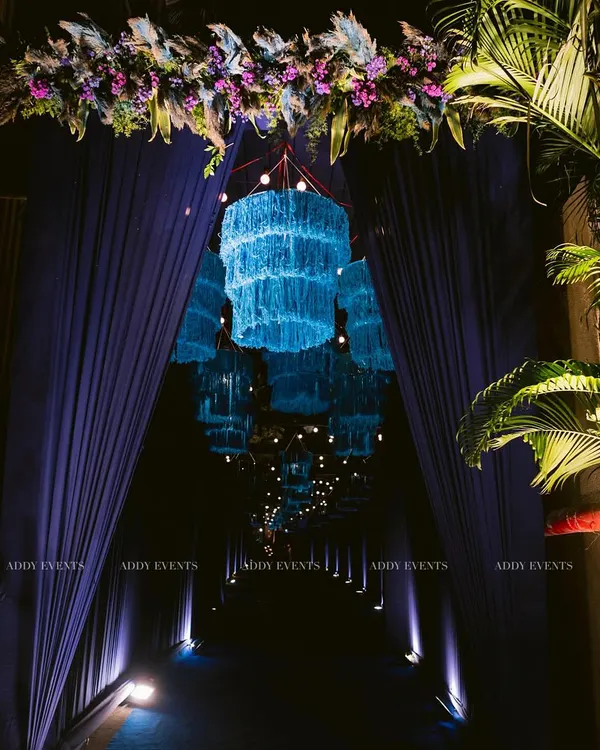 We believe the event experience begins at the entrance. This immersive walkway, featuring a tunnel of glowing blue chandeliers and dramatic drapery, creates a grand and memorable first impression for guests attending an exclusive corporate function or evening gala.