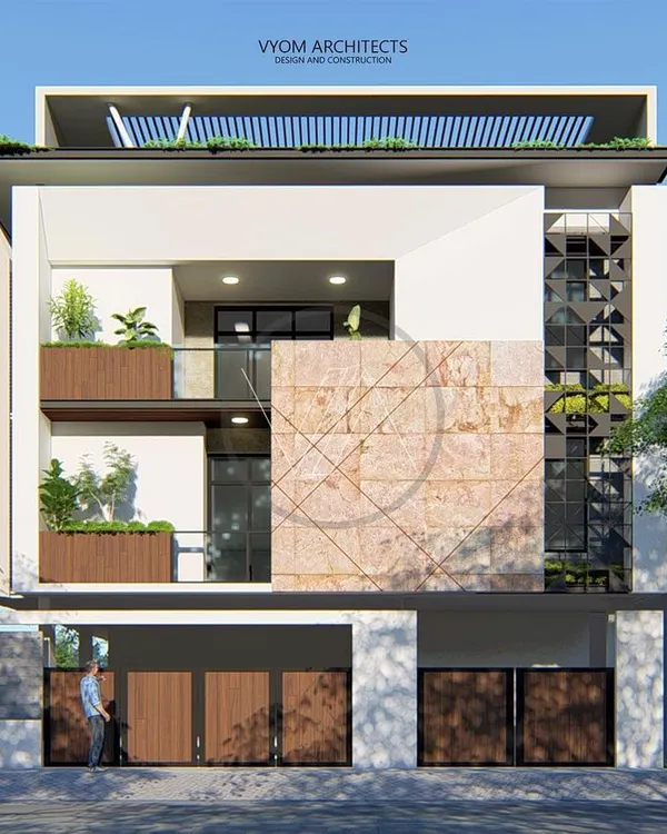 A full view of the Dasharatha residence in Bangalore. This design focuses on a simple, clean aesthetic, using natural stone cladding and a geometric MS jali screen to create a modern yet timeless facade that interacts beautifully with the surrounding greenery.