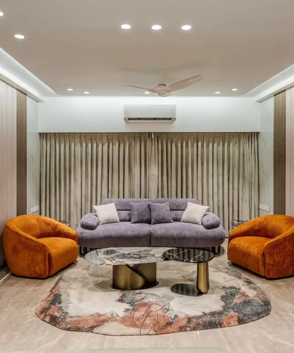 A wide view of a contemporary living room, showcasing a harmonious blend of a lilac sofa and bold orange swivel chairs. The space is defined by seamless, floor-to-ceiling custom millwork and hidden doors, ensuring a clean, uncluttered look.