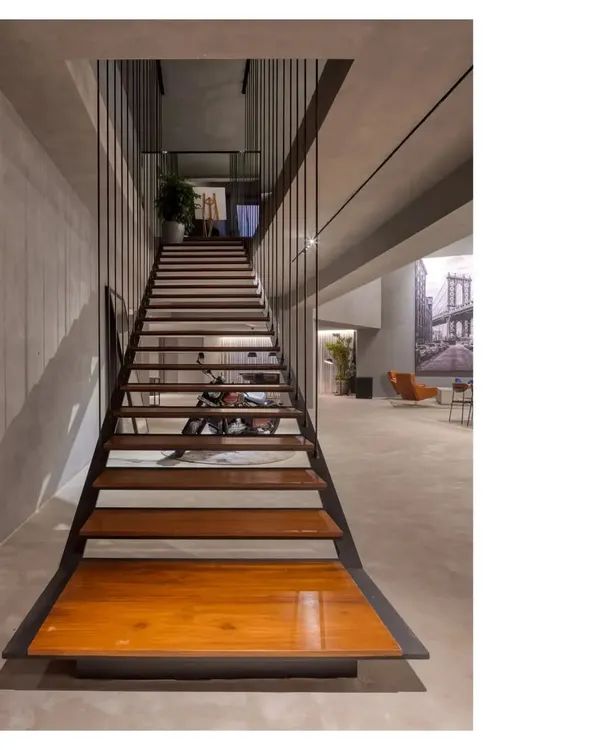 A seamless gray concrete gallery and party space. We designed this area to be highly adaptable, with a long communal table and a dramatic staircase, allowing atmosphere and people to make the space.