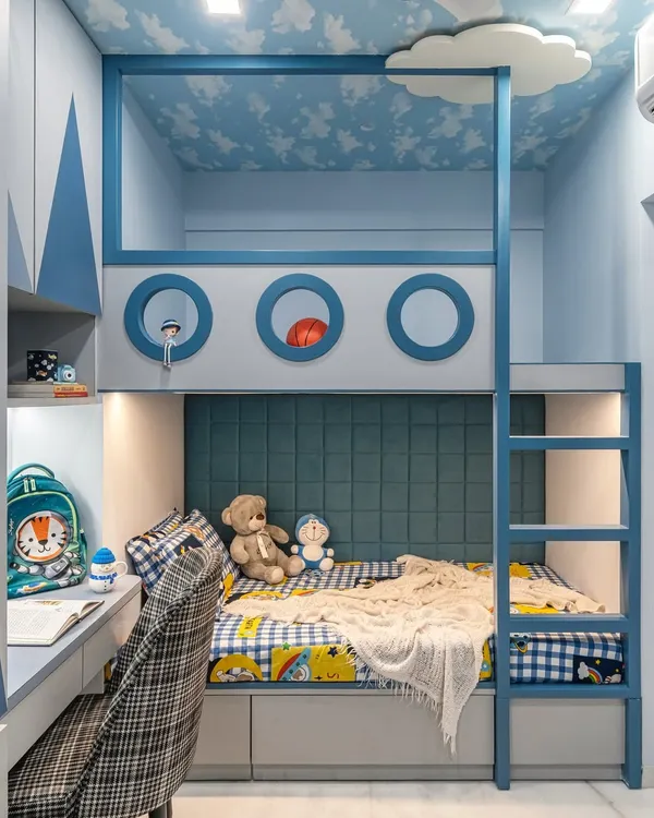 A closer look at the custom bunk bed, showing the playful porthole details and the cozy lower bunk with its upholstered headboard. The cloud-painted ceiling and built-in ladder complete this imaginative, nautical-themed design.