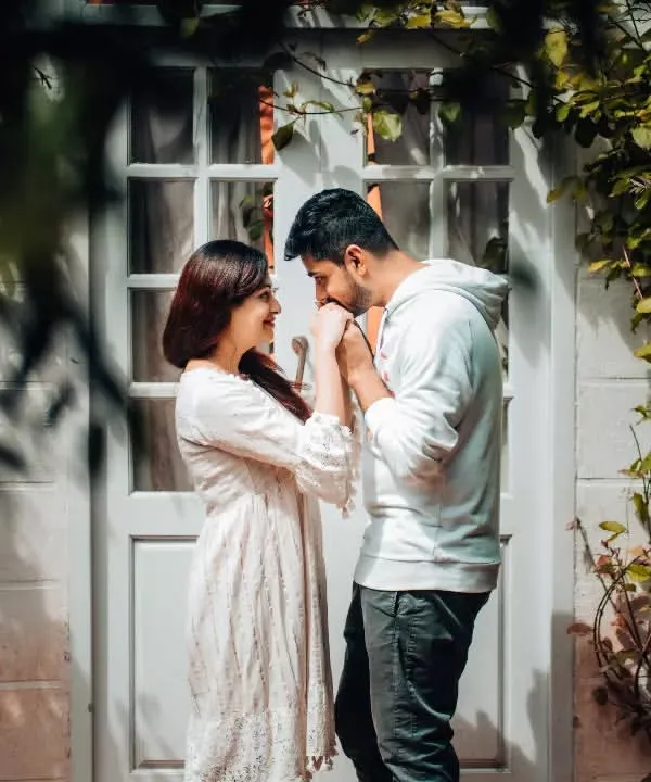 A tender moment shared between a couple, framed by natural greenery. This pre-wedding photo captures the gentle intimacy and quiet promises that are part of every love story.