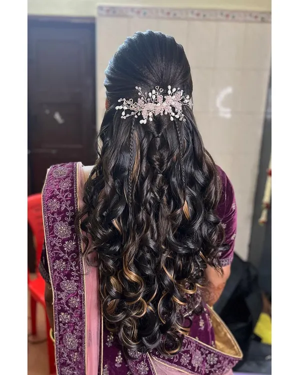 This is a popular reception hairstyle. It features a half-updo with cascading curls, accented with two delicate braids and a sparkling hair vine for a touch of glamour.