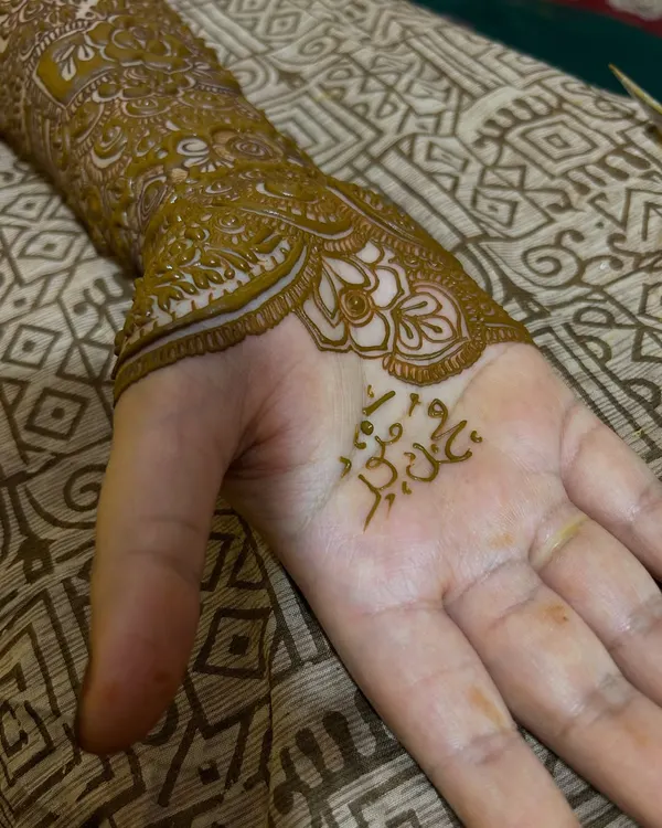 A close-up of the palm, where the groom's name is beautifully written in Arabic script, nestled within the intricate patterns.