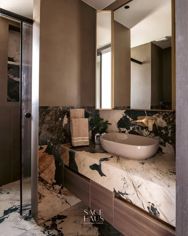 Powder rooms are an opportunity to be bold. Here, I used a dramatic, book-matched marble for the countertop and backsplash, creating a powerful artistic statement. The rich brown walls and minimalist basin complete the luxurious feel.