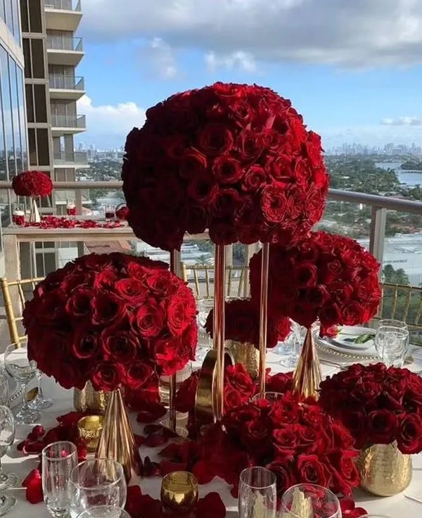 The epitome of romance and luxury. These tall centerpieces, featuring large, perfect spheres of red roses, create a dramatic and passionate atmosphere for an exclusive dinner setting.