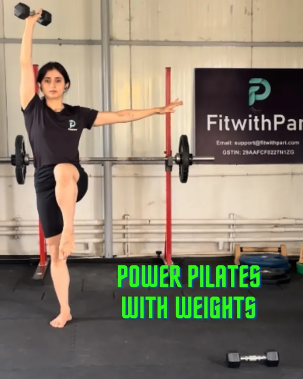 This is Power Pilates, where we use weights to add a new layer of challenge. This standing single-leg hold with an overhead press targets balance, core stability, and shoulder strength all at once.