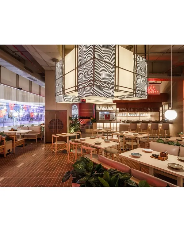 A wide view of the Lucky Chan dining area, showing the interplay between the large, graphic pendant lights and the various seating zones. The design ensures an open feel while maintaining intimate pockets for dining.