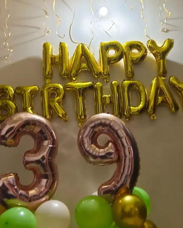 A simple and stylish home birthday decoration. This setup with foil number balloons and a 'Happy Birthday' banner is part of our affordable home decor segment, perfect for intimate celebrations.