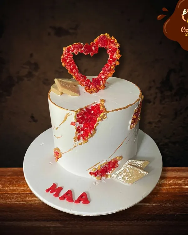 A modern and artistic cake for "Maa." This design features a white fault line style with red crystal details and a beautiful heart-shaped topper, showing love in a contemporary way.