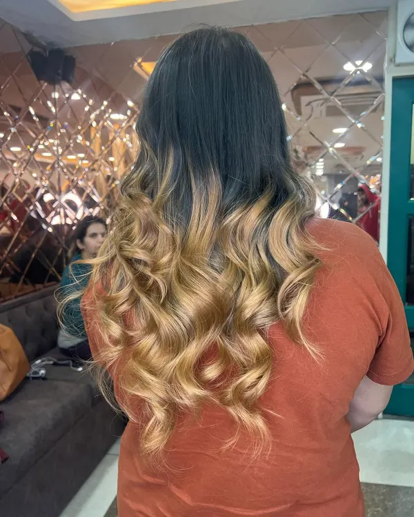 A stunning blonde ombre effect, transitioning from a darker root to bright, beautifully curled ends. This is a perfect example of a high-contrast, expertly blended look.