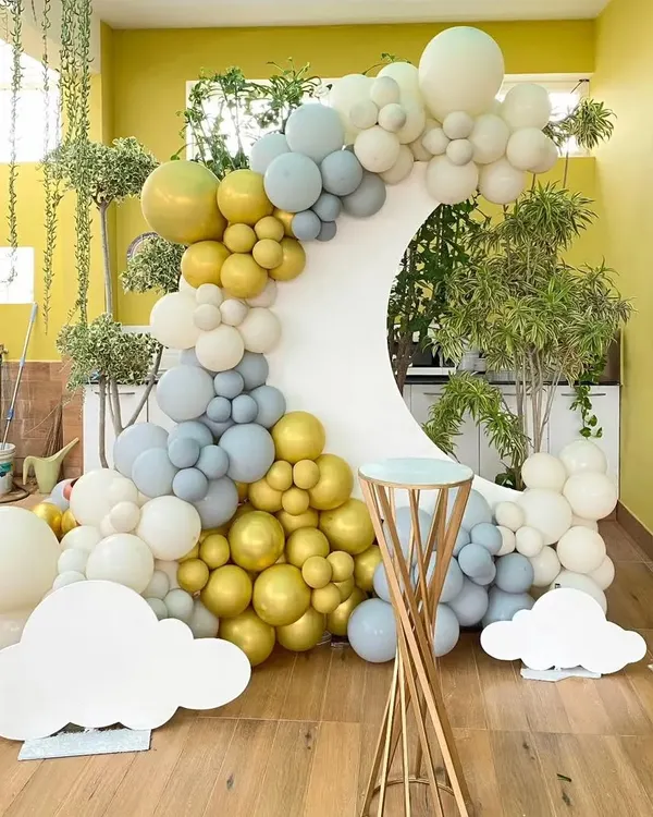 A beautiful and modern backdrop with a crescent moon shape. The balloon garland in shades of gold, grey, and white creates a sophisticated and dreamy look, perfect for a baby shower or elegant birthday.