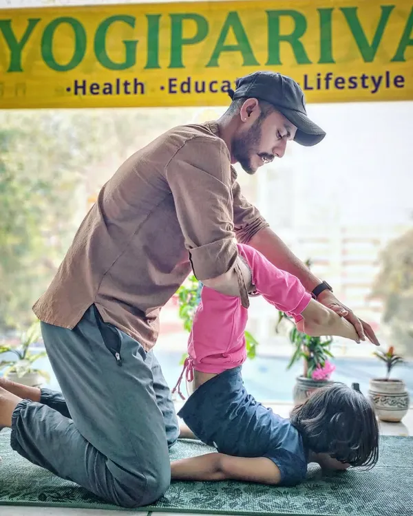 Our instructor provides gentle assistance to a young student in a backbending pose, ensuring safety and encouragement.