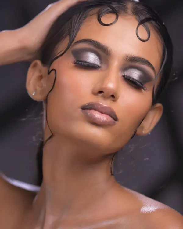 An example of a high-fashion wet look. Students learn to sculpt hair using gels and other products to create these artistic, fluid shapes, paired with a dramatic silver and black eye.