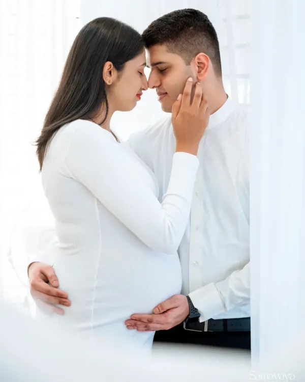 A beautifully intimate moment, forehead to forehead, capturing the deep connection between the expecting parents. A timeless black and white studio portrait.