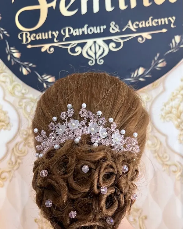 A close-up of a romantic bridal updo. This style combines soft curls and a crystal tiara, a technique we cover in our advanced hairstyling course.