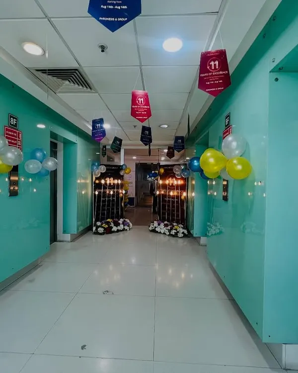 This is a corridor view of an office anniversary celebration I decorated. I used hanging banners and balloon clusters to guide guests towards the main event area.