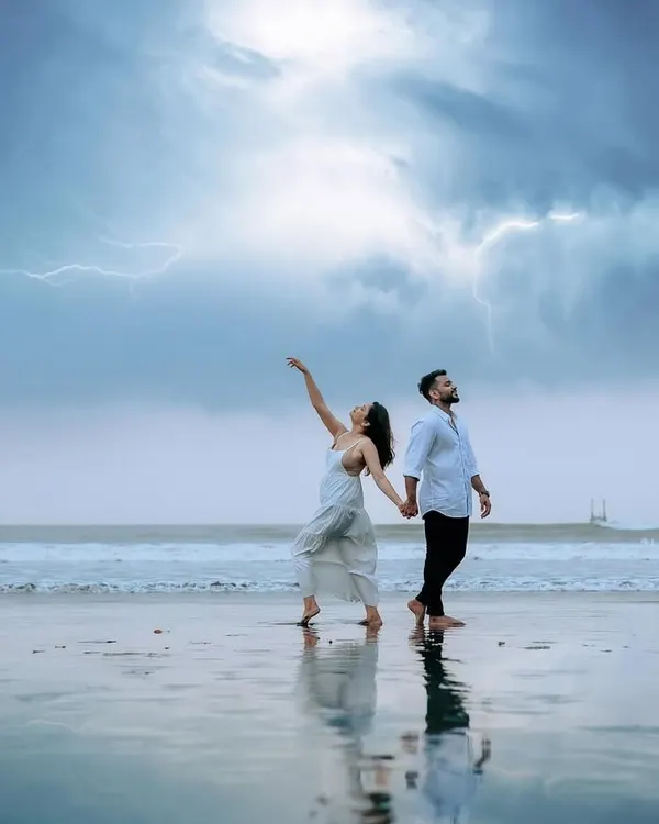 A truly epic and dramatic pre-wedding shot. The couple stands on the wet sand as lightning strikes across the stormy sky, creating a powerful and unforgettable image of their love.