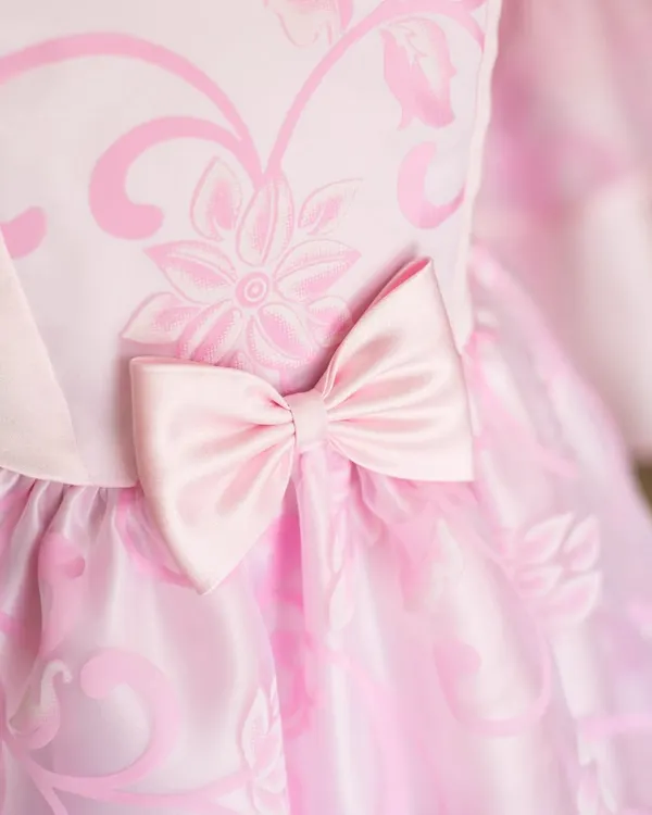 A close-up of a beautiful pink dress, showing the subtle floral pattern on the fabric and a perfectly crafted satin bow. It’s these small details that create a truly elegant finish.