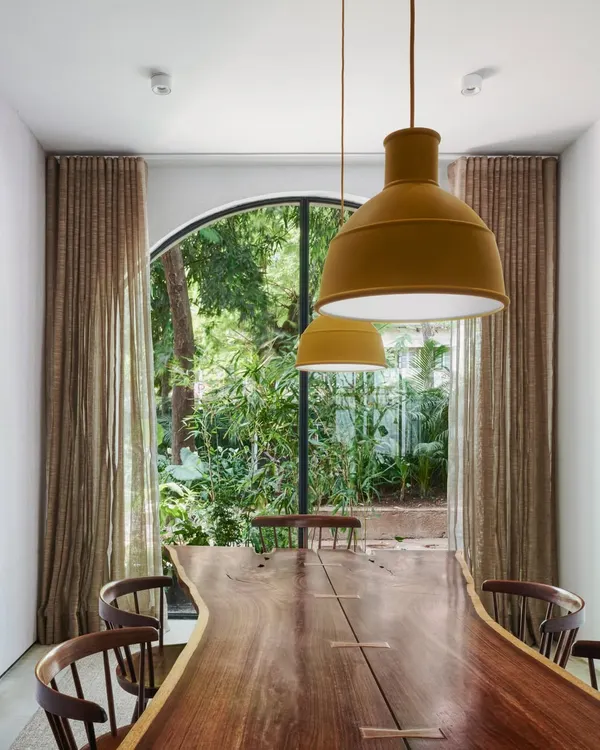 Arched French windows in our studio dining area offer a captivating glimpse into the lush greenery outside. This seamless integration of indoor-outdoor living is a core principle of our design approach.