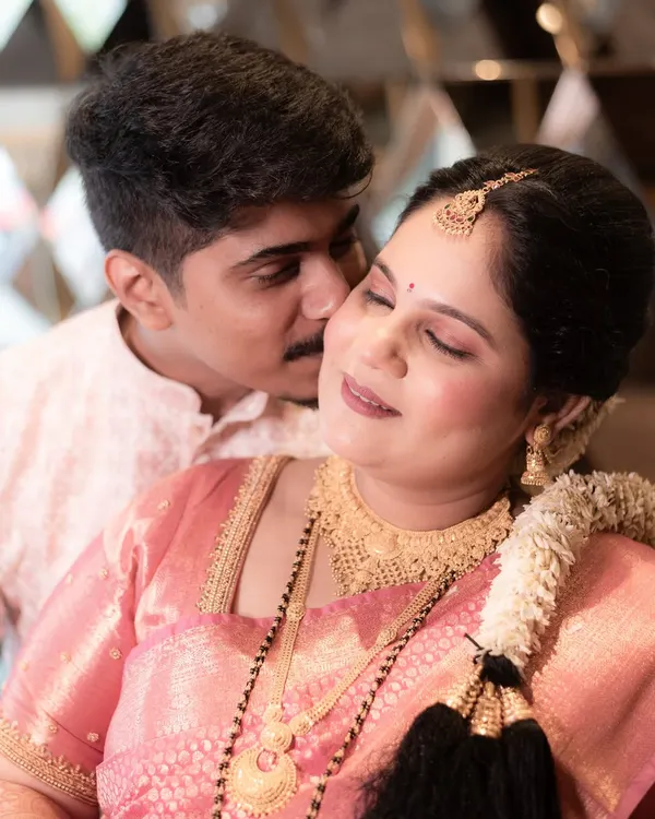 A close-up portrait filled with tenderness from a Godh Bharai celebration. This candid photo captures a sweet kiss and the serene expression of the mother-to-be, adorned in her beautiful traditional jewelry.