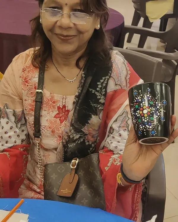 A member of the Sakhi Ladies Group proudly displays the intricate dot mandala design she painted on her mug during our art party.