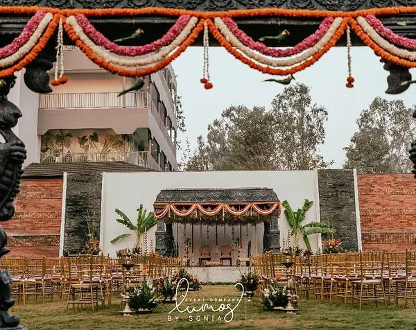 A majestic view of a South Indian temple-style wedding setup, with intricately carved pillars framing the sacred mandap. This design creates a sense of heritage and grandeur for the ceremony.