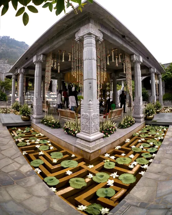 We designed a royal and romantic theme for Sonam and Ross's wedding ceremony. This stunning mandap at Amitarasa, set against the mountains, featured intricate floral hangings and a water body filled with lotuses.