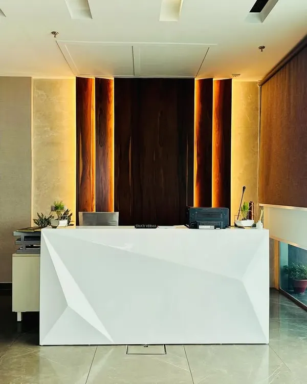 This reception area for M/s ALP in Ambala makes a powerful first impression. The design features a striking geometric reception desk, complemented by warm, vertical wood paneling with integrated backlighting and polished marble flooring to create a luxurious and professional corporate entrance.