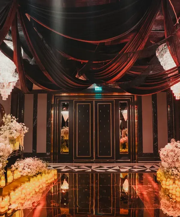 The entrance to the 'City of Dreams' after-party. We used dramatic black drapes, crystal chandeliers, and a candlelit floor to create a grand, immersive entryway for guests.