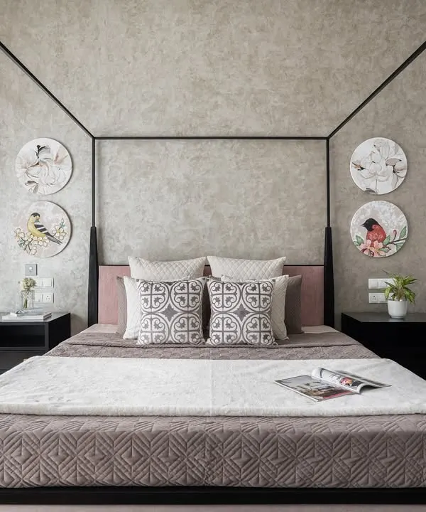 This master bedroom features a modern four-poster bed as its centerpiece. We used a textured wallpaper and circular art pieces depicting birds to add a touch of nature and personality to this earthy, tranquil space.
