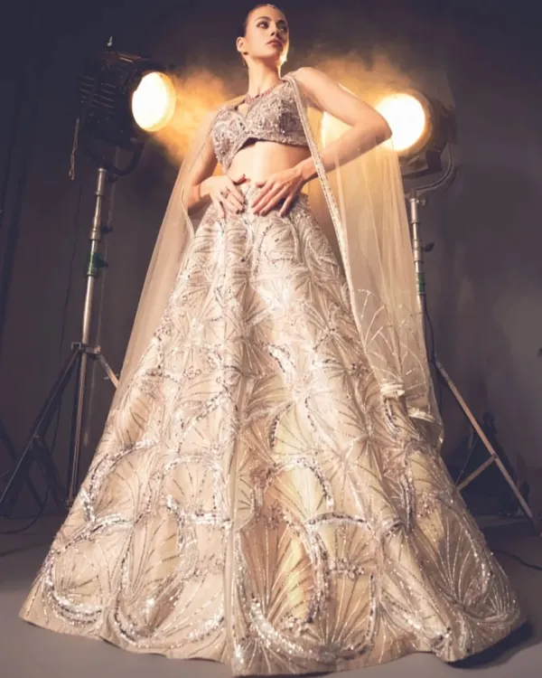 This stunning gold lehenga is a masterpiece of design and detail. The intricate, fan-like embroidery creates a sense of movement and grandeur, perfect for a bride or for making a statement at a grand celebration.