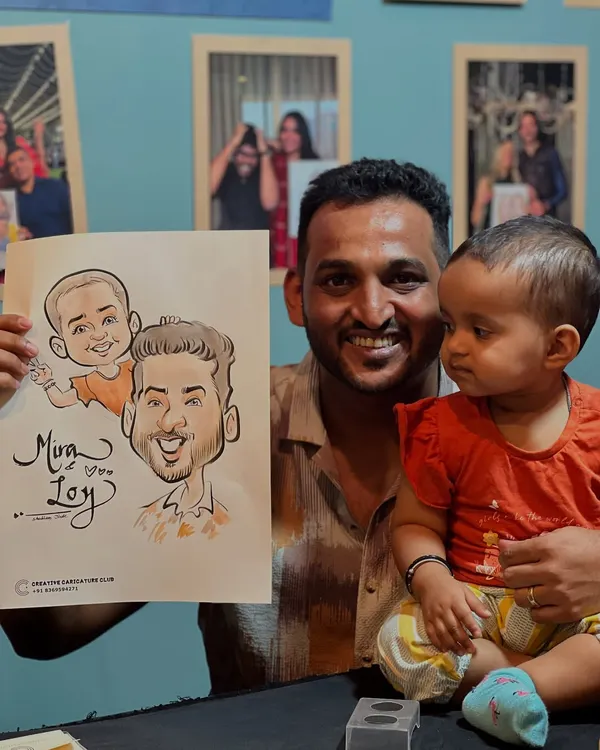 A heartwarming moment with a father and his baby girl, holding a caricature of the two of them. These are the family memories I am honored to help create.
