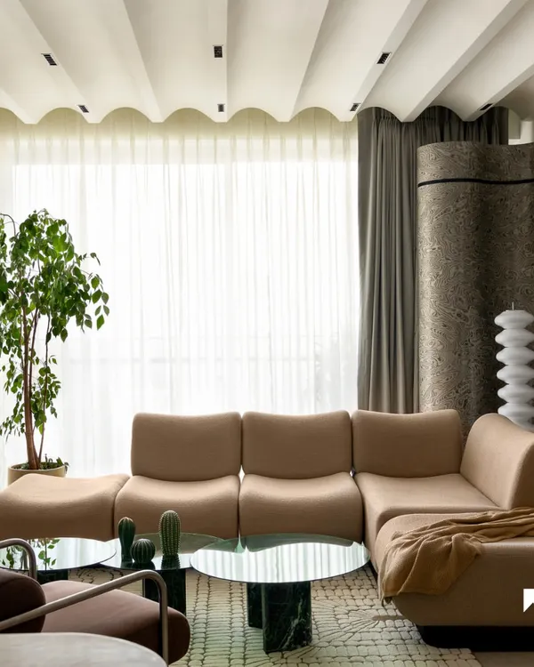 This is the heart of our 'ARAH' project, a 2130 sq. ft. Mumbai home where we had complete creative freedom. We designed the living area around a custom 16-foot caramel bouclé sofa and a bespoke marble bench, creating a space that is perfect for hosting and relaxation. The scalloped ceiling and curved terrazzo partition add a layer of avant-garde aesthetics and quiet luxury.