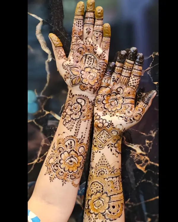 A beautiful designer mehendi with a mix of styles on each hand. One hand has a classic Indian floral pattern, while the other has a more geometric look.