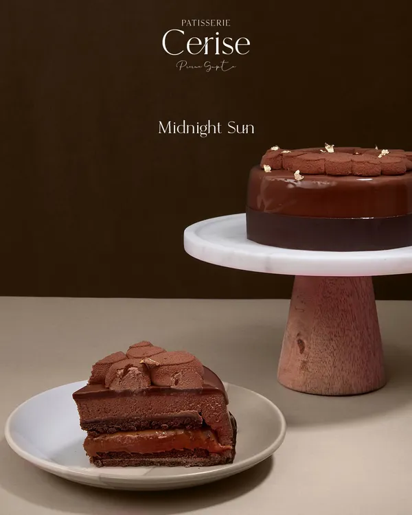 My Midnight Sun entremet, whole and sliced. It is a study in contrasts, with layers of dark chocolate mousse and a flowing salted caramel center. The glossy glaze hints at the rich journey of textures waiting inside.