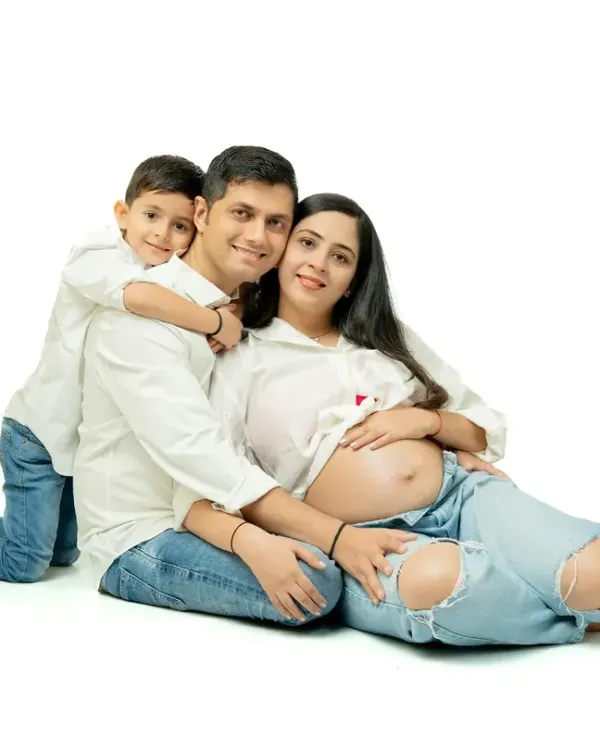 Family maternity sessions are full of joy and real moments. This shot captures the excitement of a big brother-to-be, celebrating the growing family in a relaxed, fun studio setting with casual matching outfits.