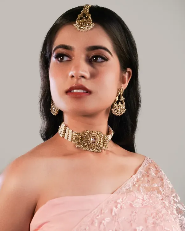 A polished makeup look for a jewellery brand shoot. The soft glam on the eyes and a neutral lip color ensure the model's beauty enhances the antique-finish choker and maang tikka without competing with them.
